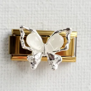 Macro shot of silver butterfly charm link with white stones on golden metal base
