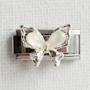 Macro view of silver butterfly charm with white opal stones on stainless steel link