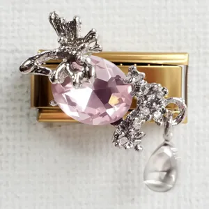 Macro view of Italian charm bracelet link with pink gemstone, silver butterfly and droplet