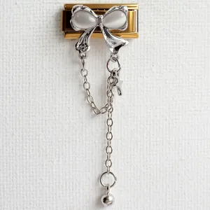 Detailed close-up of a stainless steel butterfly charm with dangling cross chains