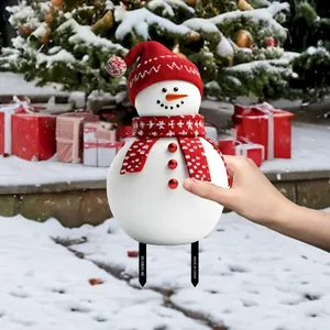 Detailed view of a PVC snowman garden stake with a red knitted hat and scarf in a snowy yard