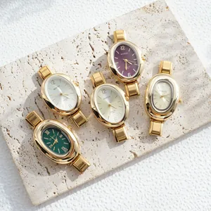 Detail view of five retro oval watches with metallic link bands on a textured stone plate