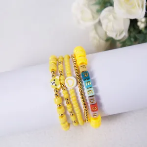 Detailed view of yellow beaded bracelet stack with FREEDOM letters and a bear charm