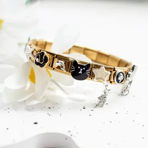 Detail of gold Italian charm bracelet featuring black flowers and dolphin charms