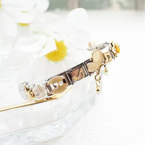 Close-up of stainless steel charm bracelet with golden musical notes and pearl details