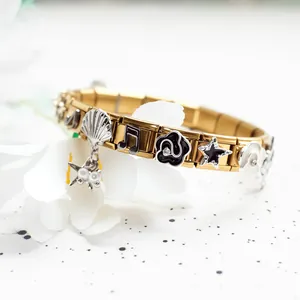 Detail of gold Italian charm bracelet featuring black enamel camellia and shell pendants