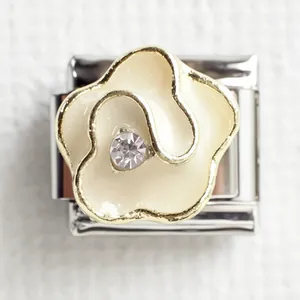 Detailed macro view of a floral Italian charm link with white enamel and golden frame