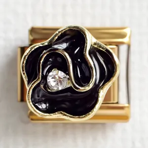 Detailed macro view of a gold-trimmed black enamel rose charm with a central zircon inlay