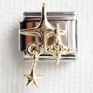Stainless steel Italian charm link with gold star pendants on a textured fabric background