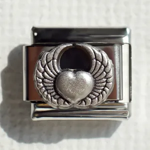 Detalle macro de eslabón italiano de acero inoxidable con corazón alado y relieve