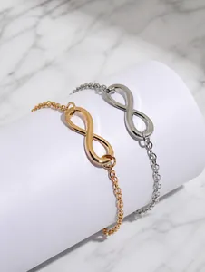 Gros plan des bracelets symbole infini en or et argent sur un support blanc épuré