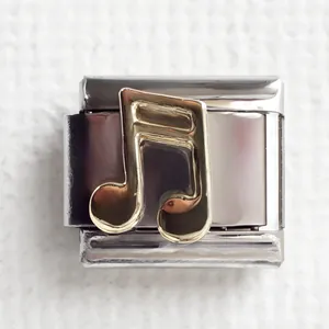Macro shot of silver stainless steel Italian charm link with a gold music note icon