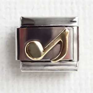 Close-up of a stainless steel Italian charm featuring a golden musical note detail