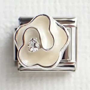 Macro shot of stainless steel Italian charm with white enamel flower and crystal inlay