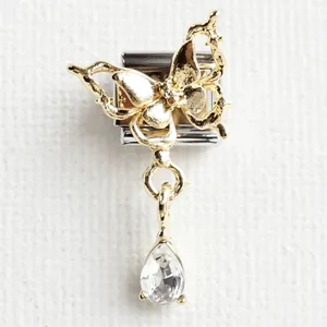 Macro shot of stainless steel charm with golden butterfly and clear crystal teardrop