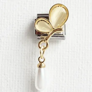 Macro detail of golden butterfly charm with cat eye stone and pearl for modular bracelet