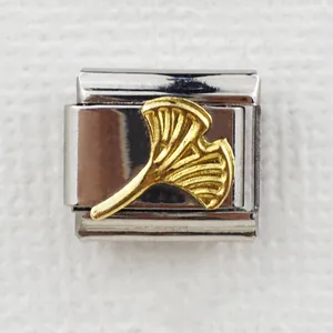 Macro shot of Italian style charm link featuring a golden ginkgo leaf on stainless steel