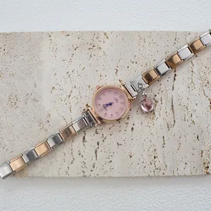 Dettaglio orologio al quarzo oro rosa con quadrante rosa, cristalli e ciondolo tartaruga