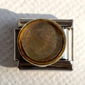 Macro detail of Italian charm bracelet link with polished silver base and brown inlay