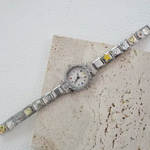 Dettaglio di un orologio a bracciale con ciondoli in smalto colorato e quadrante con strass