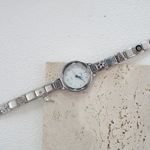Dettaglio macro dell'orologio con ciondoli in acciaio argento e pendenti a stella e torre