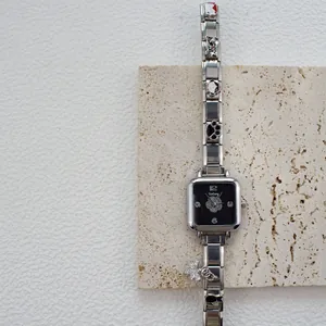 Dettaglio di un orologio al quarzo quadrato con bracciale a charm e farfalla di cristallo