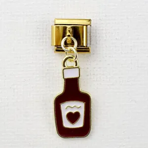 Makroaufnahme eines goldenen italienischen Charms mit rotem Flaschenanhänger und Herz