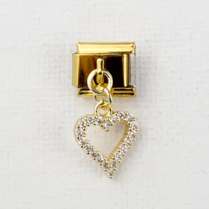 Detailed macro view of a gold-tone link charm with a sparkling pavé heart pendant