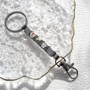 Dettaglio portachiavi modulare argento con ciondoli smaltati ape e fiori su vetro