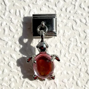 Macro detail of Italian charm link featuring a silver turtle with pink resin shell inlay