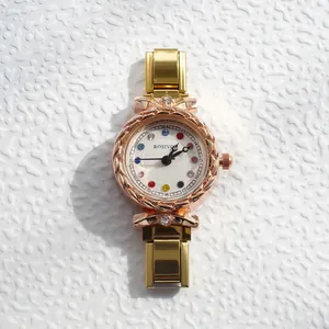 Gros plan du cadran rose doré avec index en strass colorés et lunette en métal texturé
