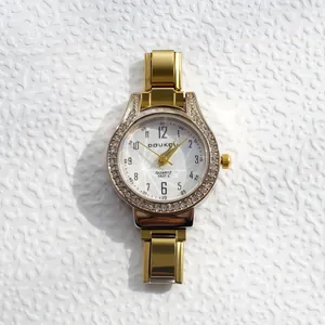 Détail de la montre à quartz dorée avec lunette strassée et cadran rayon de soleil
