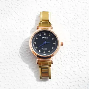 Détail d'une montre à quartz dorée avec index en diamant et aiguilles bleues sur blanc