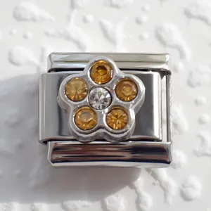 Makrofoto von Italian Charm Glied mit Bernsteinkristall-Blume auf poliertem Edelstahl