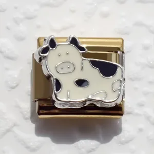Close-up of gold-plated stainless steel modular charm with black and white enamel cow design