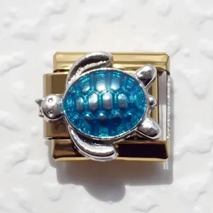 Macro detail of Italian modular charm with golden base and blue enamel sea turtle design