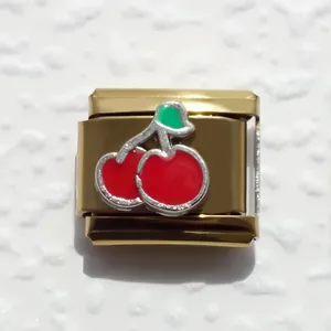 Detalle de eslabón italiano de acero inoxidable dorado con diseño de cerezas rojas