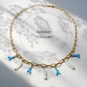 Detail van de 45cm gouden ketting met blauwe koraal en witte vis bedeltjes met schaduw