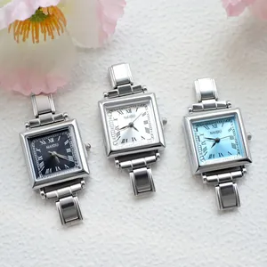 Detail of square quartz watches with black, white and blue dials on floral background