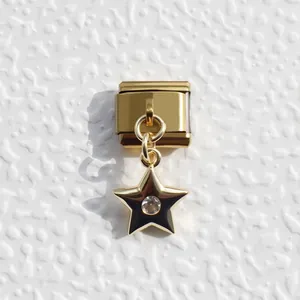 Detail of a gold modular bracelet charm with a black star and sparkling center stone