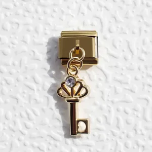 Detailed macro view of golden crown key charm with zircon on modular bracelet