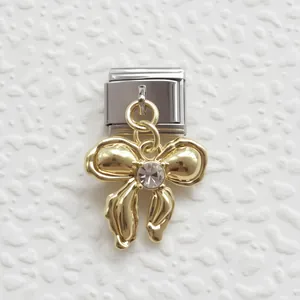 Dettaglio della maglia charm italiana con ciondolo a fiocco dorato e strass trasparente