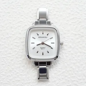Detail of silver square quartz watch with white dial and polished steel band on texture