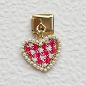 Dettaglio di un link charm italiano con pendente a cuore, motivo a quadretti e perle