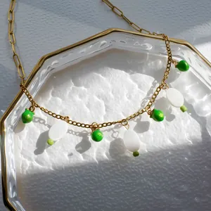 Zomerse gouden ketting met groene kralen en witte ovale hangers in schelpstijl