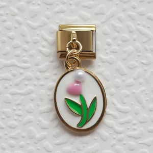 Dettaglio di un charm italiano dorato con fiore in smalto rosa e perla bianca