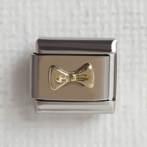 Makroaufnahme des Edelstahl-Modular-Charms mit goldener Schleife für DIY-Armbänder