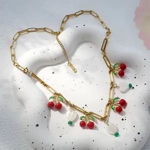 Detail van gouden ketting met geëmailleerde kersenhangers en hartvormige schelpbedeltjes