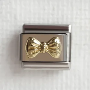 Makroaufnahme von italienischem Edelstahl-Charm mit goldenem 3D-Schleifen-Detail