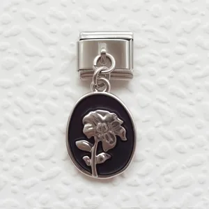 Macro detail of Italian charm bracelet link with black enamel and silver floral pendant